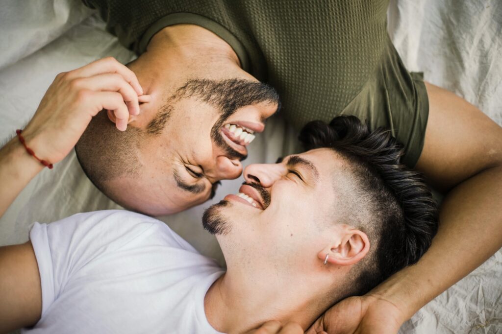 Two men laughing together in a warm, intimate moment, reflecting the joy and connection that queer-affirming couples therapy in California can help nurture.
